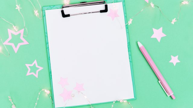 A white clipboard on a mint green backdrop surrounded by pink star shaped confetti.
