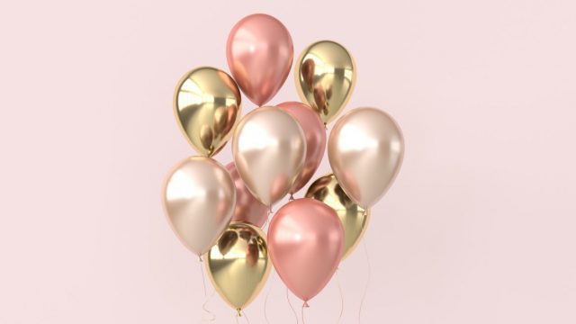 Floating balloons in front of a light pink background.