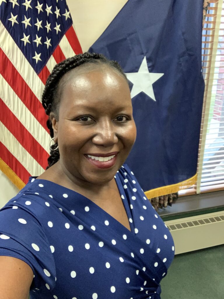 An author photo of Katrina Pringle in front of an American flag.