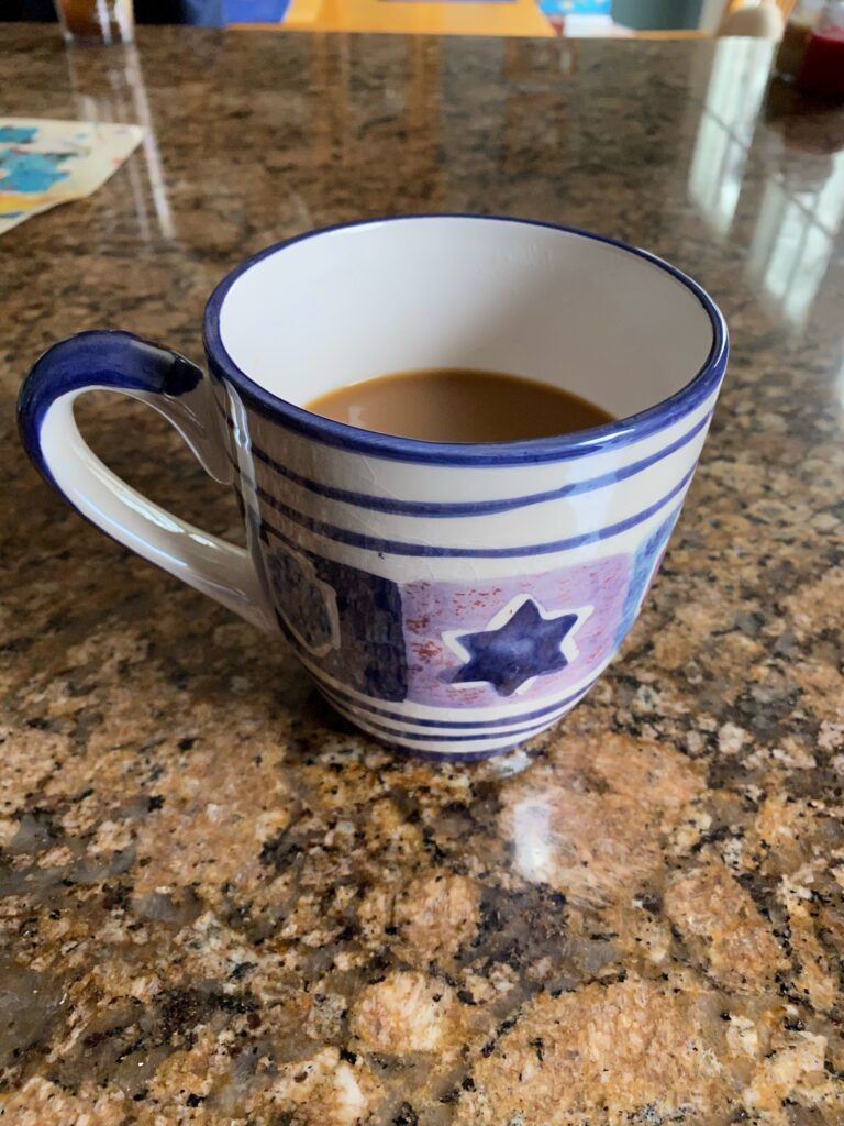 A blue and white striped mug sits on a brown marble countertop.