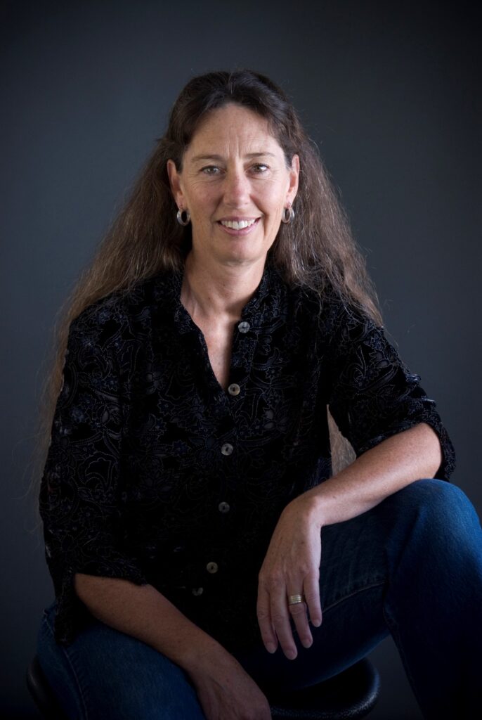 Woman with long, dark hair wearing a black shirt and jeans.