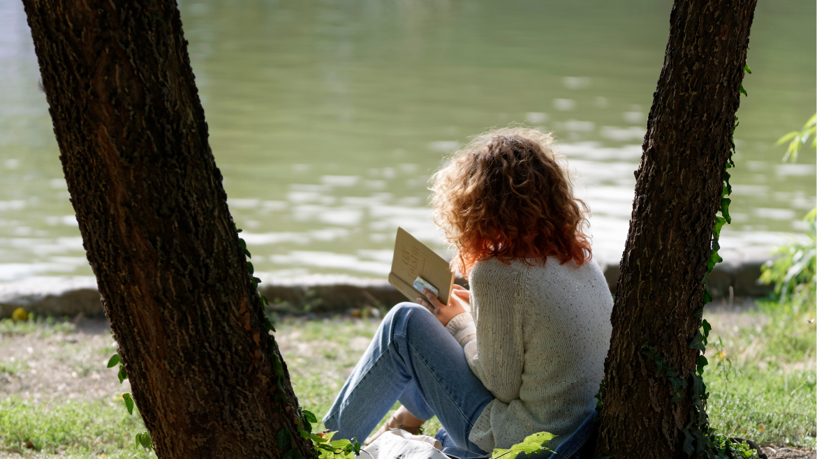 A woman reads a book under a tree