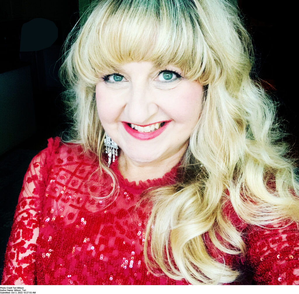 Author photo for Teri Wilson. A woman in a red top with blonde hair